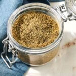 Jar of Poultry Seasoning Next to a Navy Blue Table Napkin